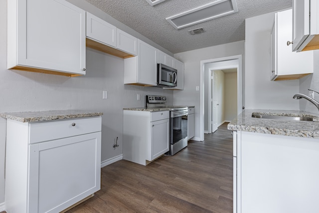 kitchen with appliances with stainless steel finishes, a textured ceiling, sink, white cabinets, and dark hardwood / wood-style floors