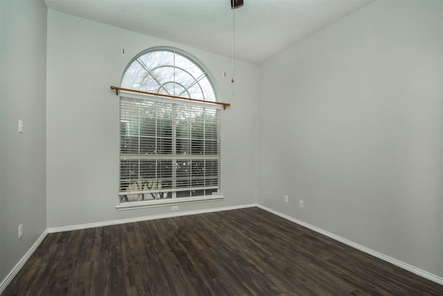 spare room with dark hardwood / wood-style flooring, lofted ceiling, and a textured ceiling