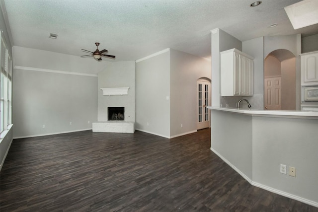 unfurnished living room with ceiling fan, sink, dark wood-type flooring, and a textured ceiling