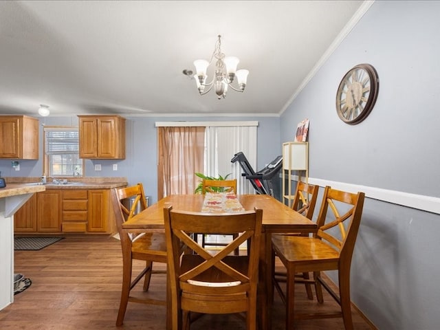 dining space with a notable chandelier, sink, light wood-type flooring, and ornamental molding