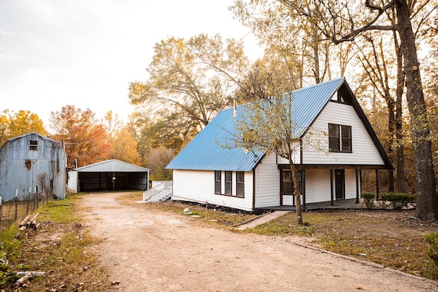 view of property exterior with covered porch and an outdoor structure