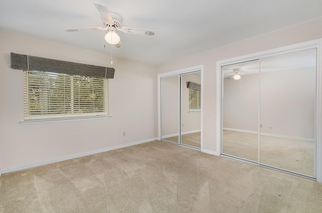 unfurnished bedroom featuring light carpet, two closets, and ceiling fan