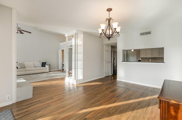 living room featuring ceiling fan with notable chandelier, dark wood-type flooring, and a textured ceiling