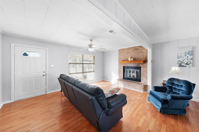 living room with a fireplace, ceiling fan, hardwood / wood-style floors, and ornamental molding