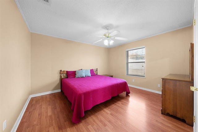 bedroom with wood-type flooring, a textured ceiling, ceiling fan, and ornamental molding