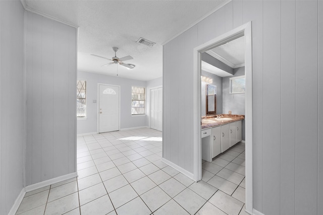 tiled foyer with ceiling fan, sink, a textured ceiling, and crown molding