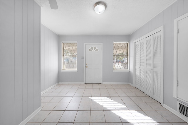 tiled foyer entrance with a textured ceiling and wooden walls