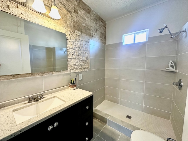 bathroom with vanity, tile patterned floors, toilet, a textured ceiling, and a tile shower