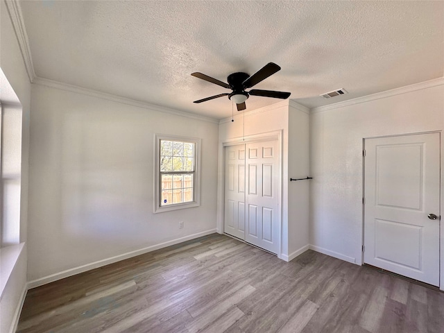 unfurnished bedroom featuring light hardwood / wood-style flooring, ceiling fan, ornamental molding, a textured ceiling, and a closet