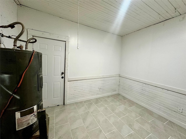 basement with wood walls and water heater