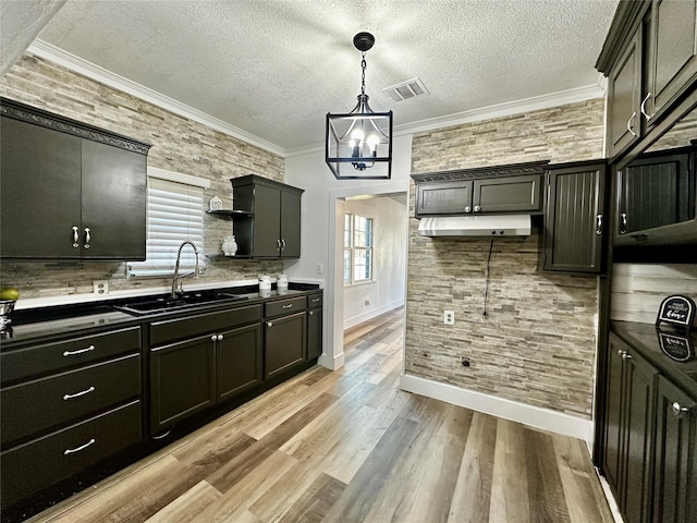 kitchen with ornamental molding, sink, pendant lighting, and light hardwood / wood-style flooring