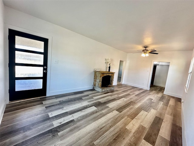 unfurnished living room featuring ceiling fan, wood-type flooring, and a fireplace