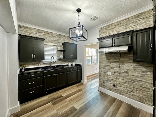 kitchen with pendant lighting, sink, light hardwood / wood-style floors, and a textured ceiling