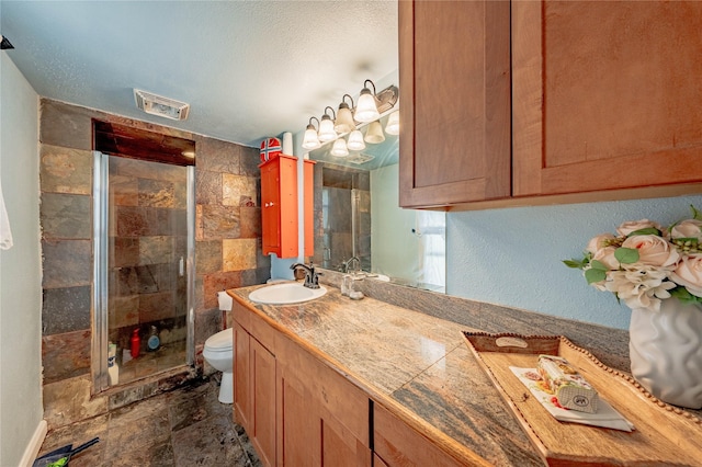 bathroom featuring vanity, a textured ceiling, a shower with shower door, and toilet