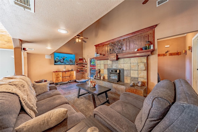 carpeted living room featuring ceiling fan, a wood stove, a textured ceiling, and high vaulted ceiling