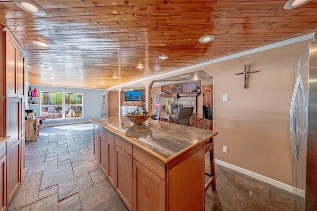 kitchen with stainless steel fridge, a kitchen breakfast bar, wood ceiling, a kitchen island, and a tiled fireplace