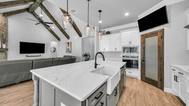 kitchen featuring appliances with stainless steel finishes, light hardwood / wood-style flooring, a kitchen island with sink, and pendant lighting