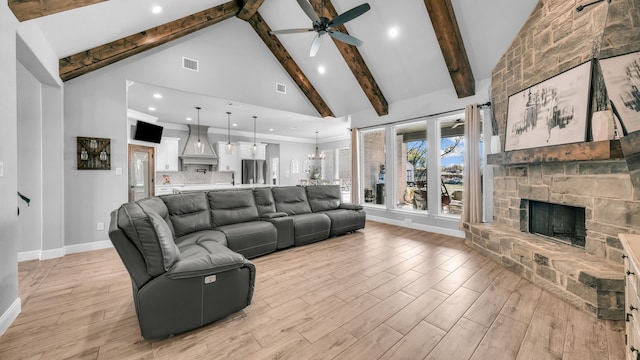 living room with a fireplace, light wood-type flooring, high vaulted ceiling, and ceiling fan with notable chandelier