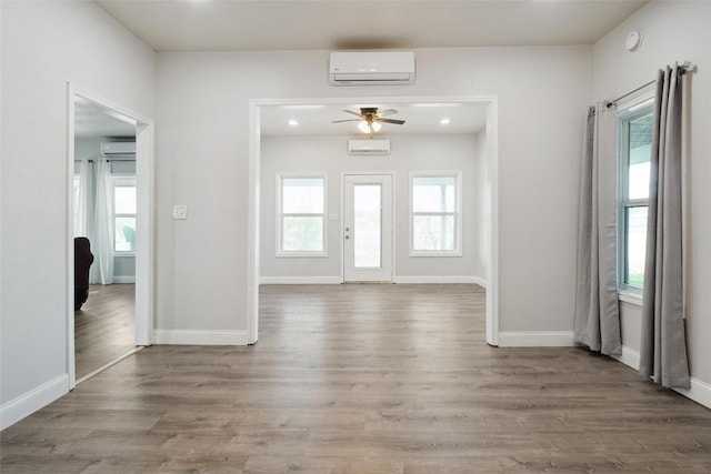 foyer entrance featuring hardwood / wood-style flooring, an AC wall unit, and plenty of natural light