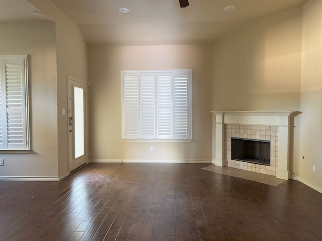 unfurnished living room with a tile fireplace, lofted ceiling, and dark hardwood / wood-style floors