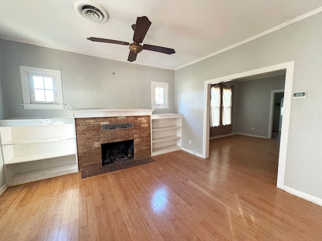 unfurnished living room featuring hardwood / wood-style floors, ceiling fan, ornamental molding, and a fireplace