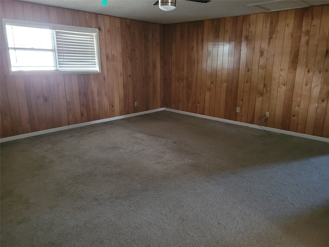 carpeted empty room with a textured ceiling and wooden walls