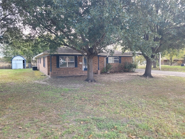 ranch-style house featuring central AC unit, a storage shed, and a front lawn