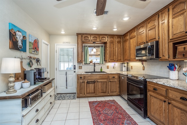 kitchen featuring appliances with stainless steel finishes, light stone counters, light tile patterned floors, and sink