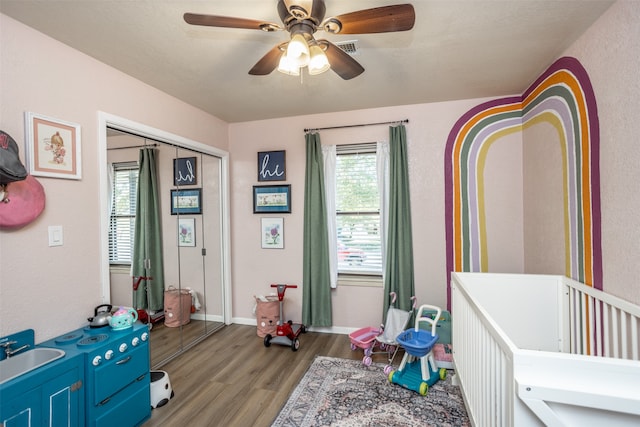 bedroom featuring ceiling fan, light hardwood / wood-style flooring, multiple windows, and a closet