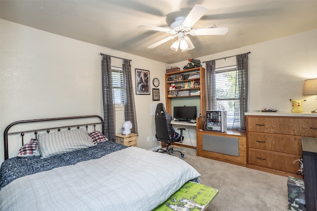 bedroom featuring ceiling fan, built in desk, and light carpet