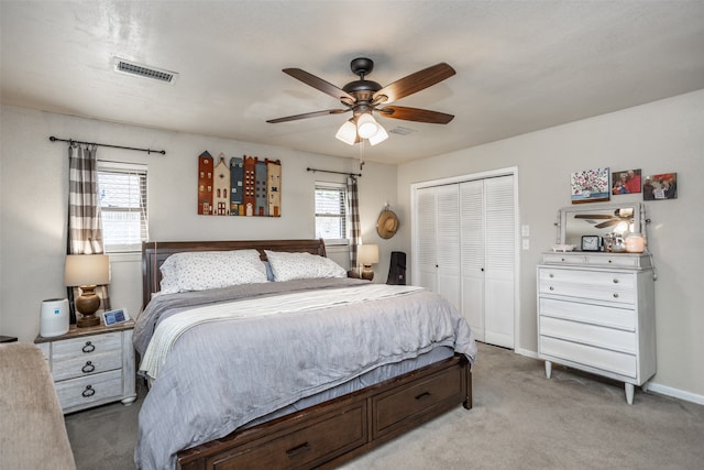 bedroom featuring ceiling fan, a closet, light carpet, and multiple windows