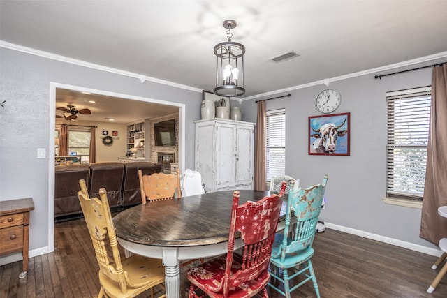 dining area featuring dark hardwood / wood-style floors, ceiling fan, ornamental molding, and a fireplace