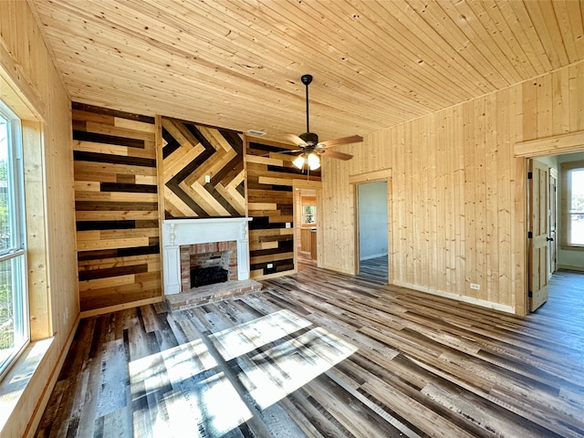 unfurnished living room featuring wooden walls, plenty of natural light, ceiling fan, and hardwood / wood-style flooring