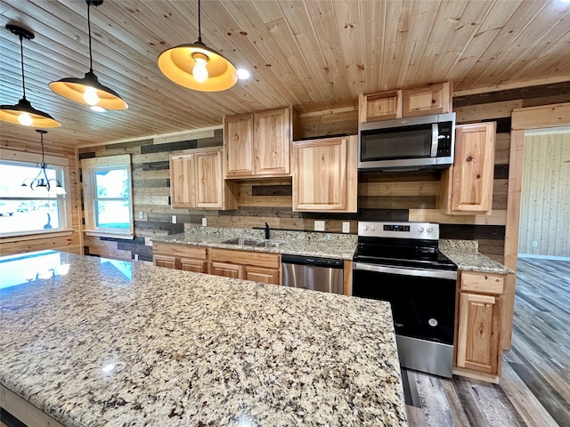 kitchen featuring wooden walls, decorative light fixtures, and appliances with stainless steel finishes