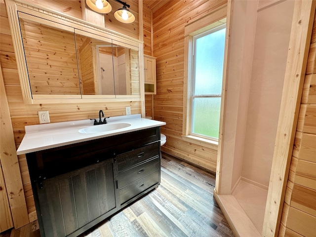 bathroom with hardwood / wood-style floors, vanity, and wood walls