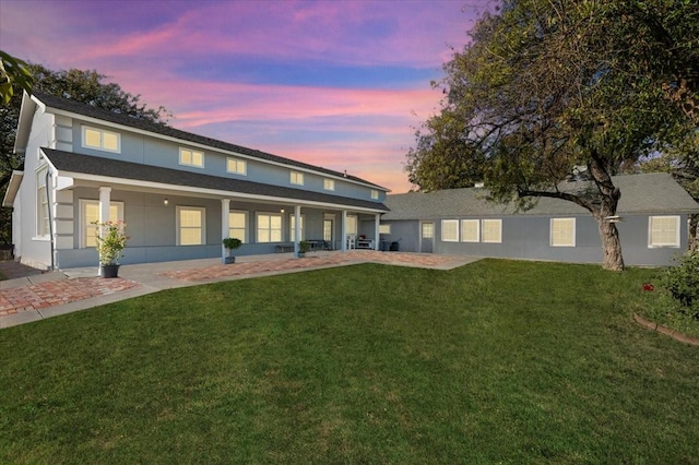 back house at dusk with a lawn