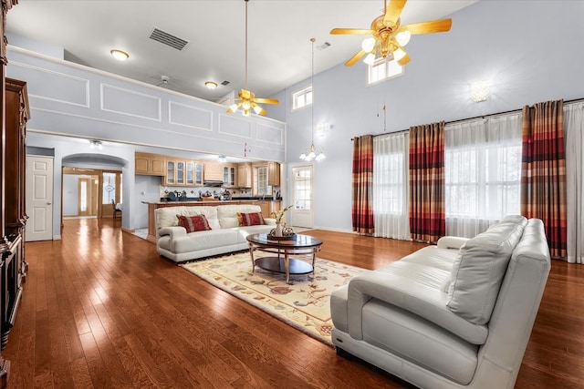 living room featuring ceiling fan with notable chandelier, plenty of natural light, high vaulted ceiling, and dark hardwood / wood-style floors