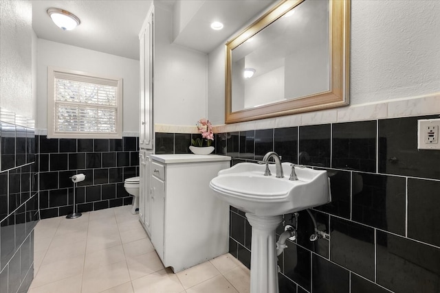 bathroom with tile patterned floors, toilet, and tile walls