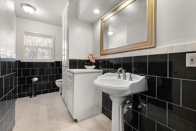 bathroom with tile patterned flooring, tile walls, and toilet