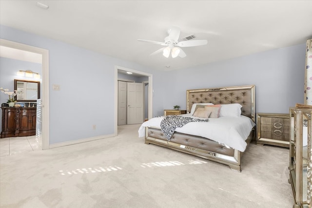 bedroom with ceiling fan, light carpet, and connected bathroom