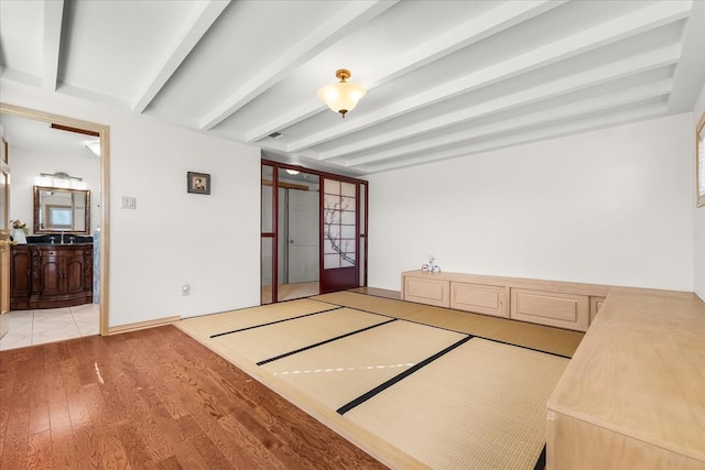 interior space featuring basketball hoop, light wood-type flooring, and beamed ceiling