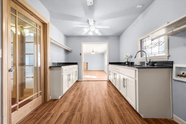 kitchen featuring white cabinets, ceiling fan, light hardwood / wood-style floors, and sink