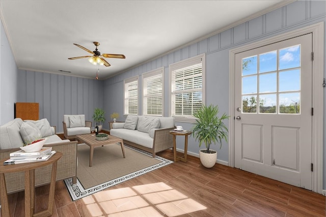 living room featuring hardwood / wood-style flooring, ceiling fan, and crown molding