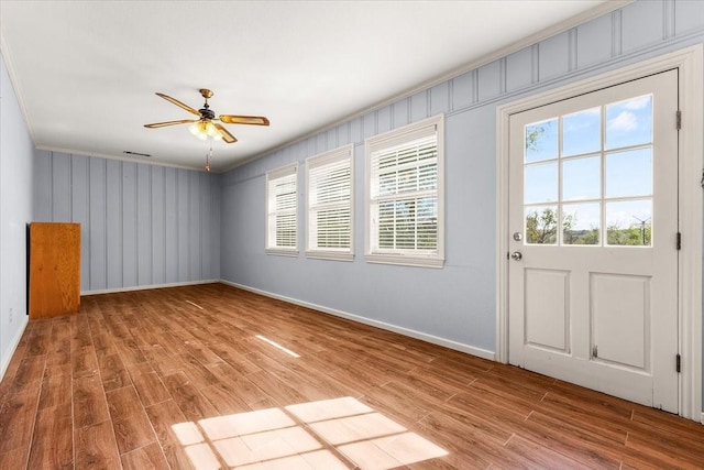 interior space with wood-type flooring, ornamental molding, and ceiling fan