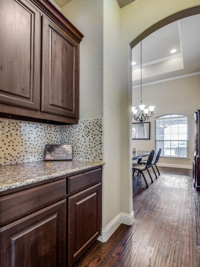 bar featuring baseboards, tasteful backsplash, a tray ceiling, and dark wood-style flooring