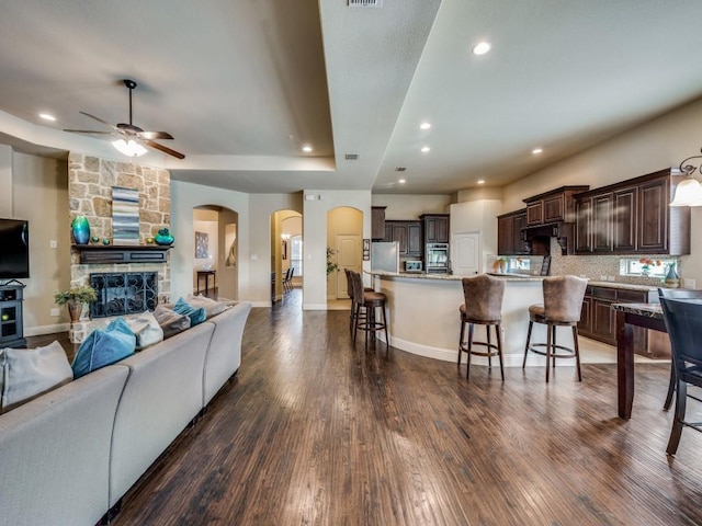 living area featuring dark wood-style floors, arched walkways, a fireplace, and recessed lighting