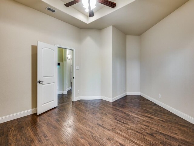 living room featuring dark hardwood / wood-style flooring, ceiling fan, a fireplace, and a tray ceiling