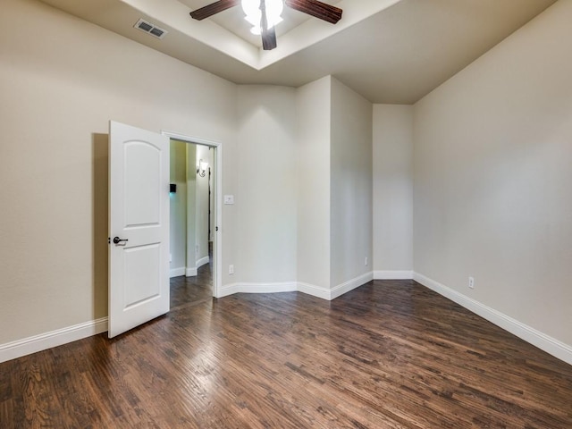 unfurnished room featuring visible vents, baseboards, a raised ceiling, a ceiling fan, and dark wood-style floors