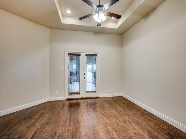 spare room with ceiling fan, dark hardwood / wood-style floors, and a raised ceiling