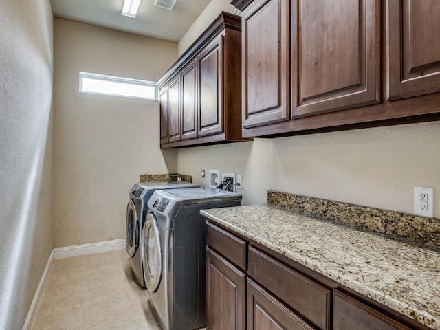 laundry room with washer and dryer, light tile patterned floors, and cabinets